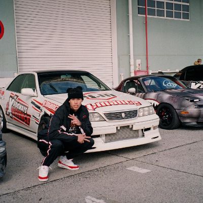 Bernie Martinez posing for a picture in front of cars in Tokyo, Japan.